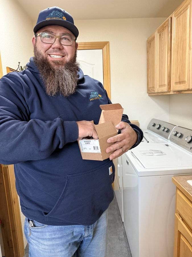 Austin unboxing a replacement fixture in a laundry room